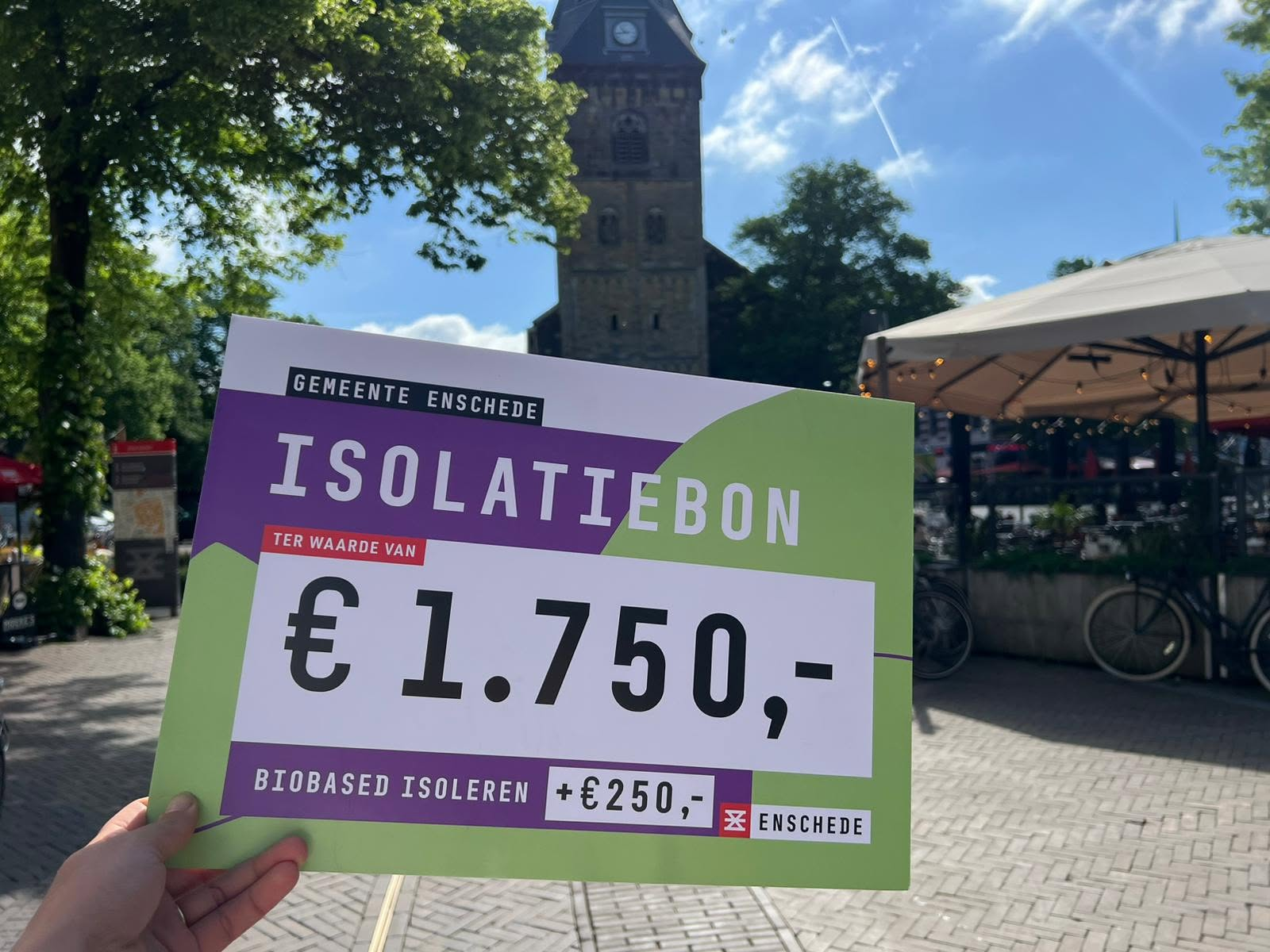 Isolatiebon van €1.750,- voor woningisolatie, uitgedeeld door een man in pak voor een muur vol bonnen.